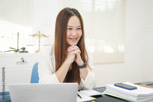 A cheerful businesswoman works at her office desk as a legal consultant, handling online civil cases, including debt disputes, unfair dismissals, foreclosures, land redemptions, with professionalism photo