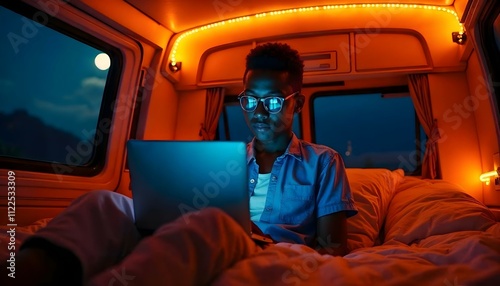 Young freelancer working remotely on laptop in camper van at night