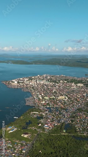 Aerial view of Surigao City with buildings and houses. Blue sea bay and clear skies and clouds. Mindanao, Philippines. Vertical view. photo