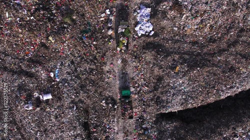 Trucks full of trash moving along big landfill. Garbage dump with non-recyclable waste, unsorted plastic. Human impact to the nature, environmental pollution