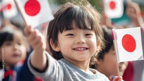 A Joyful Young Girl Holds Japanese Flag, Celebrating National Pride and Culture in a Crowd of Children photo