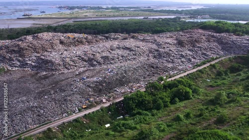 Aerial view of big garbage dump surrounded by greenery, environmental pollution, waste accumulation, ecological impact. Eco-documentaries or awareness. Waste heap shot in Bali, Indonesia