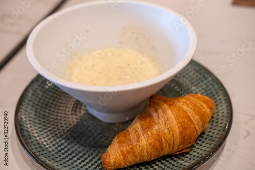 Croissant, a buttery pastry with a bowl of soup.