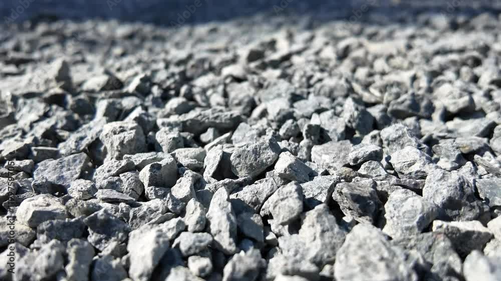 Crushed Stone Texture: Close-up view of grey crushed stones, ideal for construction, landscaping, or design projects.  The image showcases the rough texture and irregular shapes of the stones. 