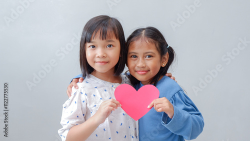 Cute little children with red hearts on grey background. Valentine's Day celebration.