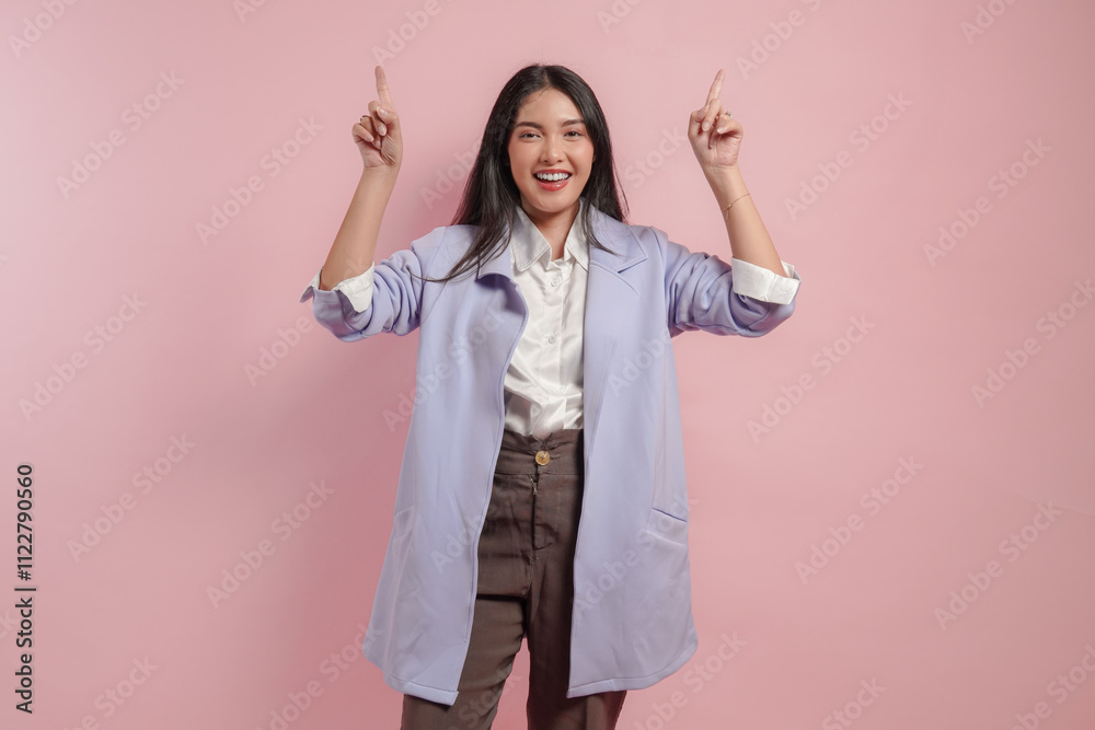 Joyful young woman wearing purple coat and pointing to the copy space upwards.