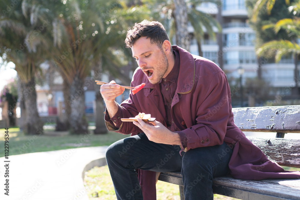 Fototapeta premium Young caucasian man eating sashimi at outdoors
