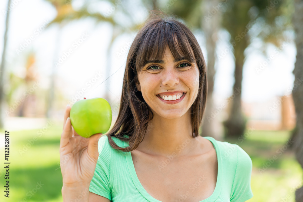 Young woman with an apple at outdoors smiling a lot Young woman with an apple at outdoors smiling a lot