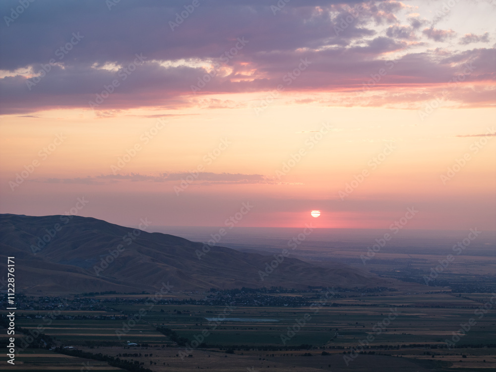 Fototapeta premium Mountain landscape in summer at sunset. Fields and lake near the mountains. Top view, drone photo.