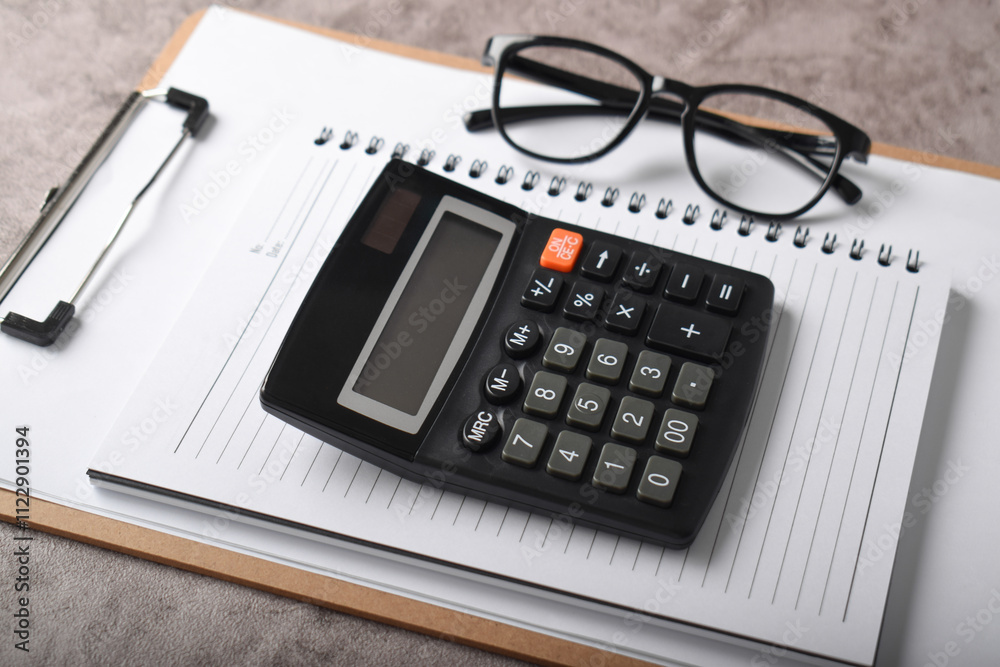 Top view office accessories calculator pen clipboard notebook isolated dark grey background. Bookkeeping workplace concept. Top view office accessories calculator pen clipboard notebook isolated dark grey background. Bookkeeping workplace concept.