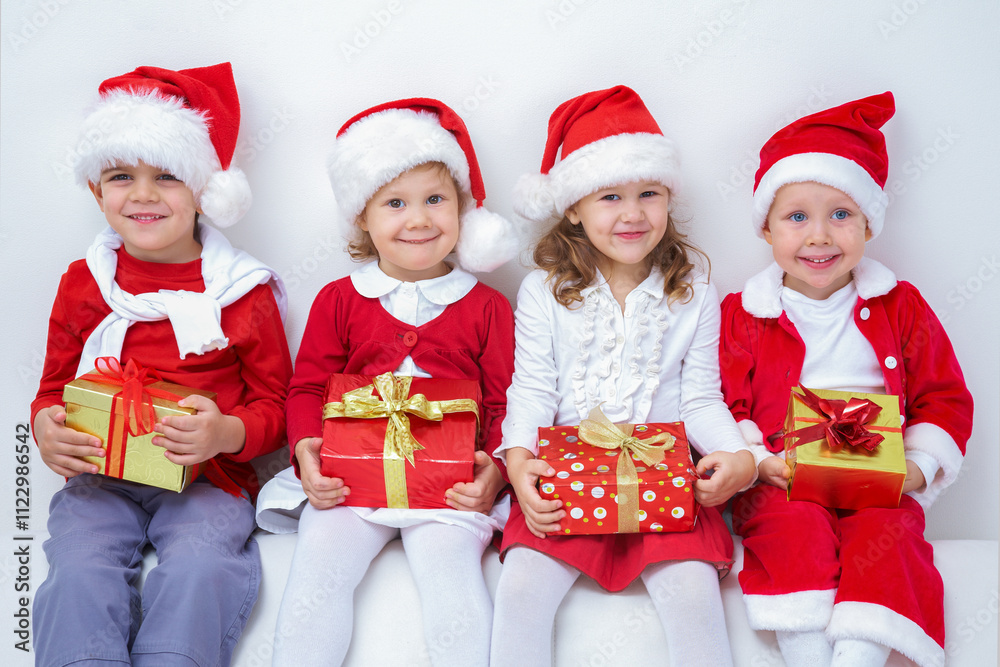 Group of four children in Christmas hat with presents