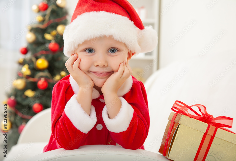 Portrait of little cute boy in Santa Claus costume with Christmas present