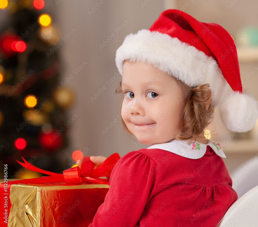 Portrait of little cute girl in Santa Claus costume with Christmas present