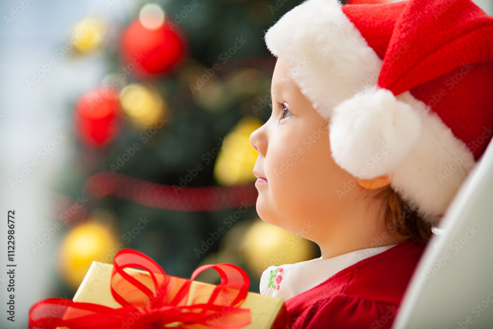 Portrait of little cute girl in Santa Claus costume with Christmas present