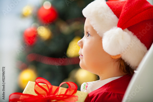 Obraz na płótnie Portrait of little cute girl in Santa Claus costume with Christmas present w salonie