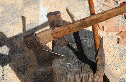 axes and hatchets embedded in a stump at a wood processing company photo