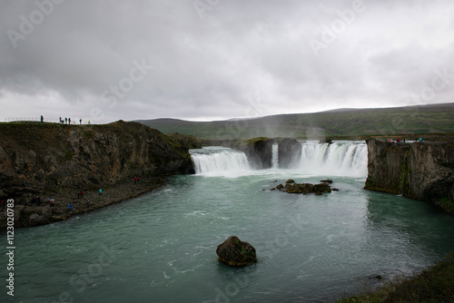 Godafoss waterfall plunging into turquoise river in iceland under cloudy sky photo