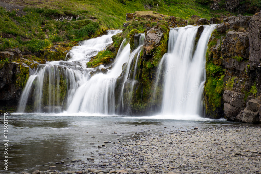 Fototapeta premium Kirkjufellsfoss waterfall plunging into a serene icelandic landscape