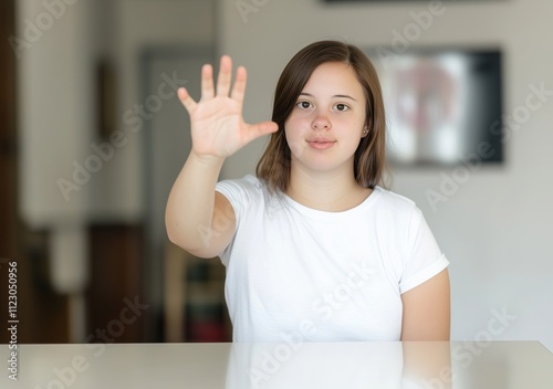 Young girl with Down's syndrome showing five fingers, stop gesture photo