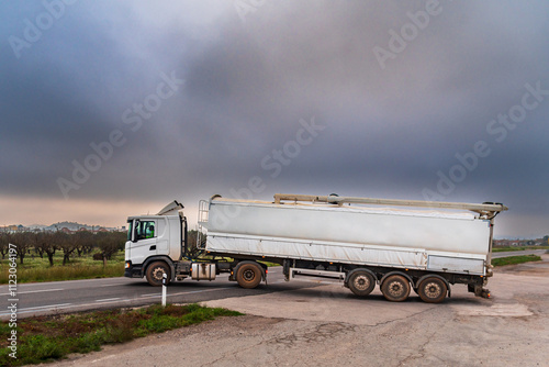 Truck with a semi-trailer specialized for transporting and delivering animal feed, merging onto a conventional road. photo