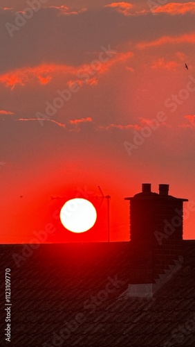 Stunning Red Sunset Sky with Silhouettes of an Old Chimney and TV Antenna