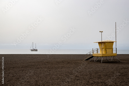 Landscape by the sea. City beach with yellow lifeguard huts on black lava beach. Bathing bay with sand in Gran Tarajal, Las Palmas, Fuerteventura, Spain photo