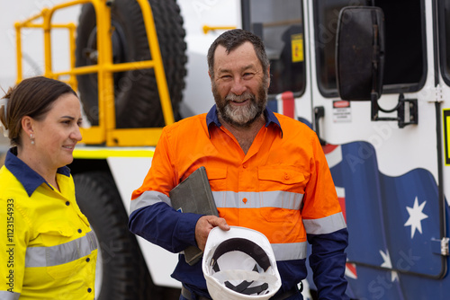 Workers in high visibility clothing standing beside australian crane truck on industrial site photo