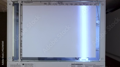 An office scanner performs the process of scanning an A3 document. Scanning paper to the MFP