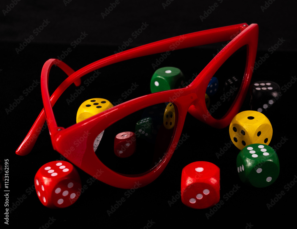 Red cat eye sunglasses and dice cubes on black background nearby