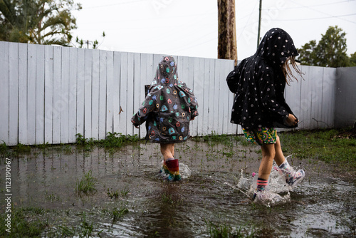 kids in gumboots and raincoats splashing in puddles photo