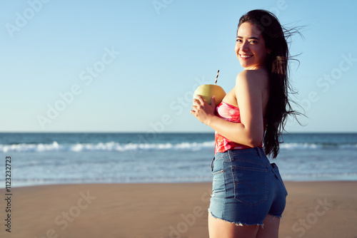 Portrait of a Latina woman holding a melon with juice on the beach on vacation in summer at sunset photo