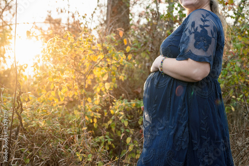 Pregnant woman belly with yellow leaves and blue dress for expecting mother surrogacy
