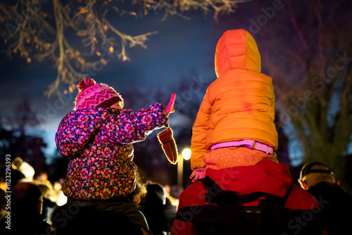 Deux enfants sur les épaules de leurs parents observent un spectacle photo