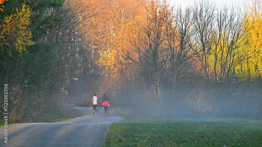 Φωτογραφία Two women jogging in the footpath in the park in a picturesque autumn scene