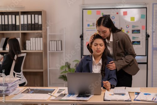 Asian businesswoman comforting her stressed colleague while working late at night in the office, providing support and empathy during a challenging moment filled with pressure and deadlines