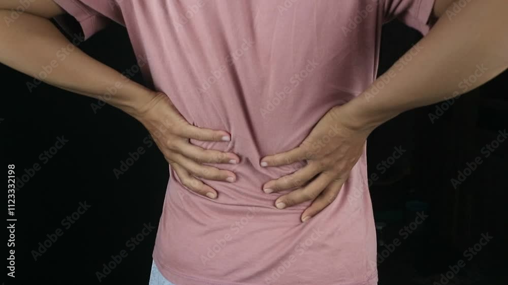Rear view, man with back pain on black background, Close up hands touching back pain