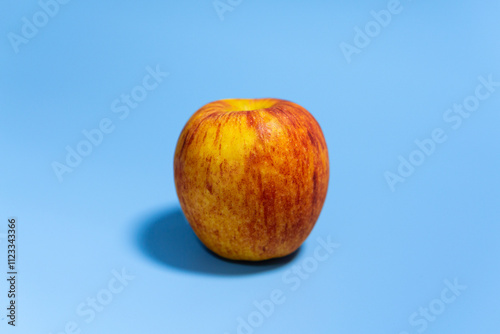 Close-up of a ripe red apple on a vibrant blue background, showcasing its fresh and natural appeal as a healthy snack.