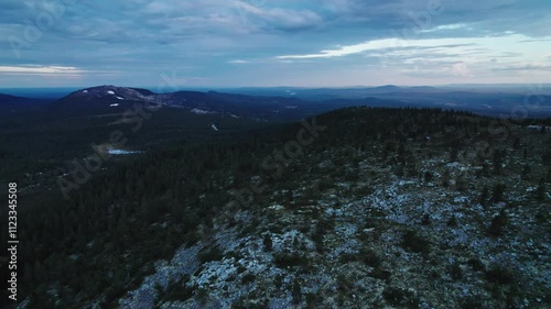 Experience a serene summer evening as a drone captures stunning views of the ski slope and rocky mountain ridge in Idre, Dalarna, Sweden, during the magical twilight hours