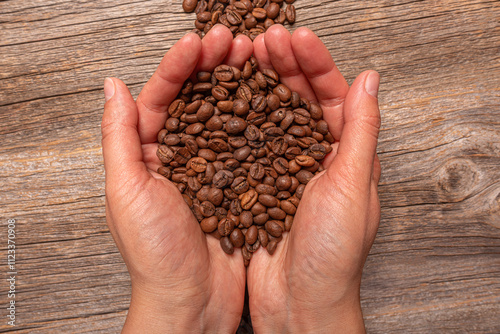 Obraz na płótnie Coffee beans in female hands on wooden background. w salonie