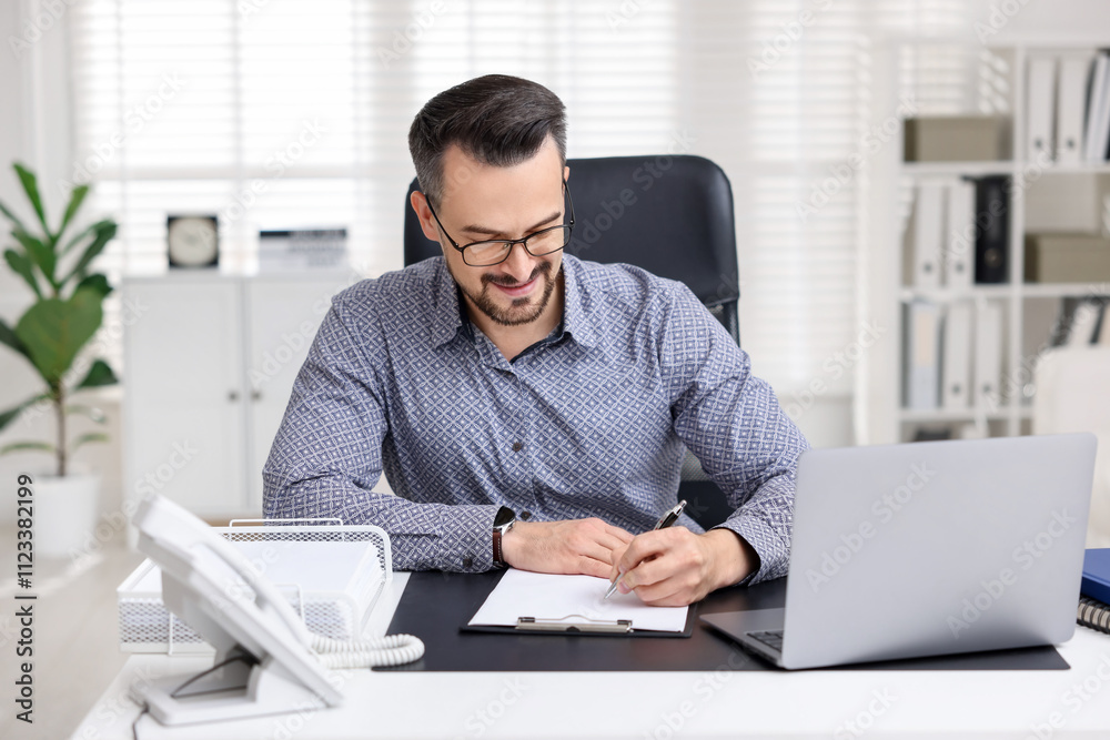 Naklejka premium Handsome banker signing document at table in office