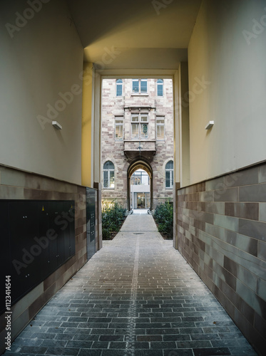 Long passageway leading to a beautifully preserved historic building in France, surrounded by stone walls and greenery photo