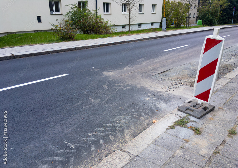 Brand new road already destroyed by reconstruction, red and white construction sign