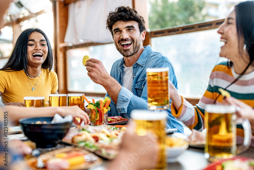 Young friends drinking and toasting beer pints at brewery bar garden - Group of people enjoying happy hour sitting bar table - Beverage life style concept, men and women having dinner party together