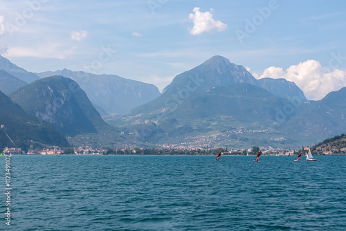 Ferry tour with scenic view of lakeside town Torbole and Riva at Garda Lake, Trentino, North Italy. Surrounded by unique rugged rock formation Monte Brione, Garda Hills. Summer lakeside vacation photo