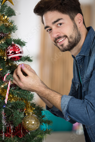 happy mid adult man decorating christmas tree at home photo