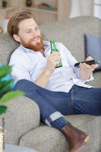 man drinking beer while watching tv on sofa