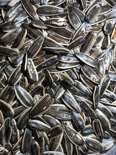 sunflower seeds backgroundThe image shows striped sunflower seeds in a close-up view. They are scattered in a random pattern, forming a dense texture of alternating light and dark stripes on each seed photo