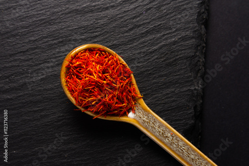 saffron spice inside of ceramic spoon  on black stone background