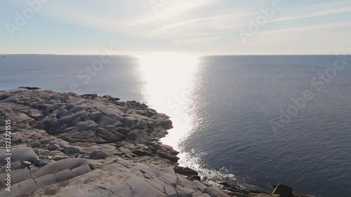 Aerial view A Lobster Boat Sails Below The Lighthouse At Peggy Cove. The Drone Aerial View Highlights The Stunning Sunset Glow Over The Nova Scotia Coastline.