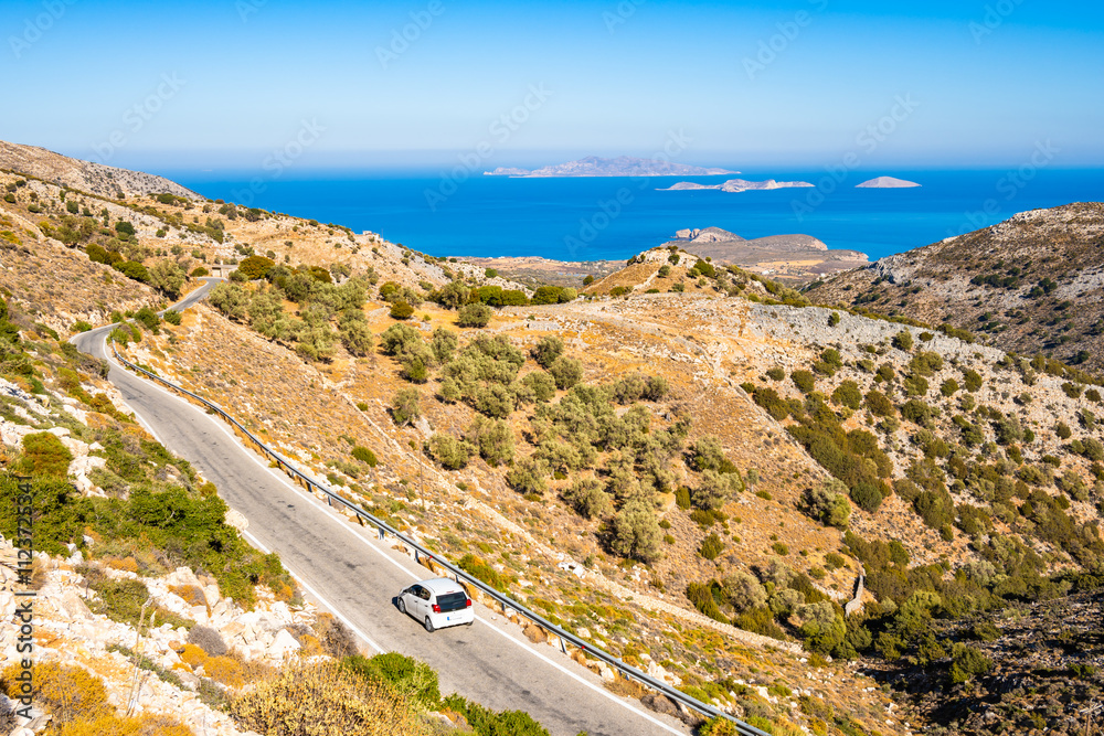 Car driving on scenic mountain road leading to sea coast, Naxos island, Cyclades, Greece